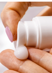 A hand squirting some cream onto fingers.
